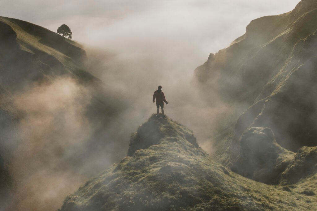 Hombre de pie en un acantilado con niebla superpuesta