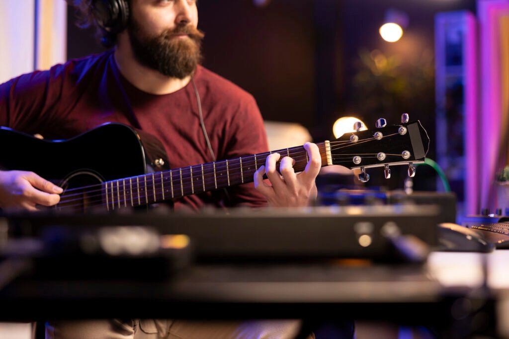 Músico tocando la guitarra y usando equipos de mezcla para crear nueva música, observando la interfaz del software DAW en la computadora. Productor grabando bandas sonoras con equipos electrónicos, ingeniería acústica.