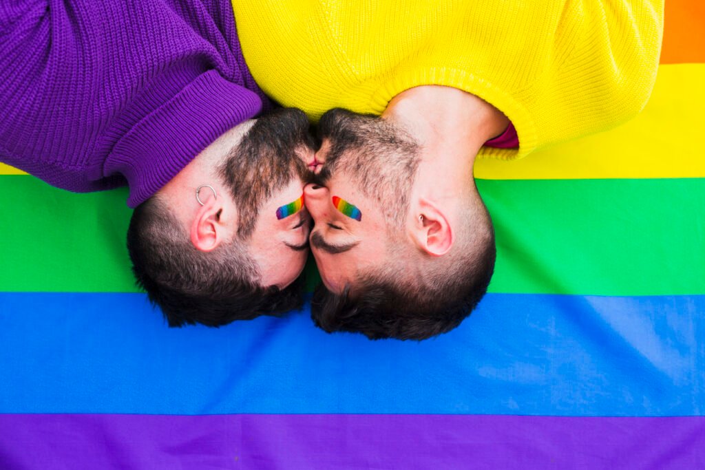 pareja de hombres lgbt besándose sobre una bandera arcoíris 